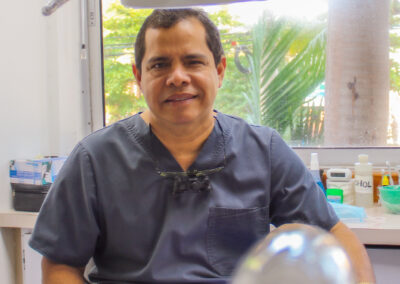 Dr. Jairo Montoya in his dental office with palm trees outside the window